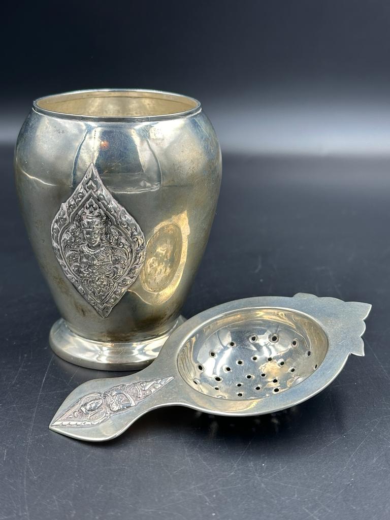 A Thai Sterling silver, embossed cup and tea strainer, approximate total weight 120g.