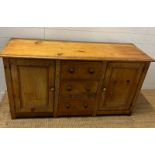 A Victorian pine dresser base with three drawers flanked by cupboards (H75cm W145cm D50cm)