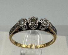 An 18ct and platinum three stone diamond ring with diamond shoulders, size N1/2