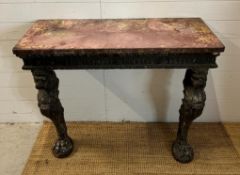 A carved console table with carved lion head supports terminating with lion paws on marble top (