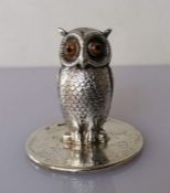 An Edwardian silver menu holder depicting an owl with amber eyes on a circular base by Sampson Morda