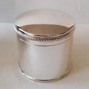 A cased Georgian-style silver cylindrical biscuit box with a domed hinged lid and gadroon rims