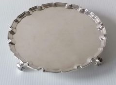A George V round silver salver with pie-crust border on four scroll feet, 20.5 cm diameter