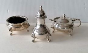 A Georgian-style silver cruet set comprising mustard, salt and pepper with carved rims