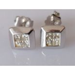 A pair of diamond stud earrings, each set with four princess-cut diamonds
