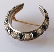 A sapphire and diamond crescent-shape brooch on yellow gold, the largest stones approximately 0.10 c