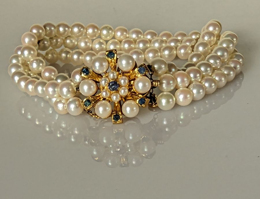 A three-strand cultured pearl bracelet with 9ct yellow gold and sapphire clasp