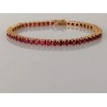 An 18ct yellow gold and ruby tennis or line bracelet in a claw setting, box clasp, 18 cm