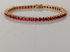 An 18ct yellow gold and ruby tennis or line bracelet in a claw setting, box clasp, 18 cm