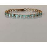 An aquamarine line or tennis bracelet in a yellow gold claw setting