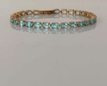 An aquamarine line or tennis bracelet in a yellow gold claw setting