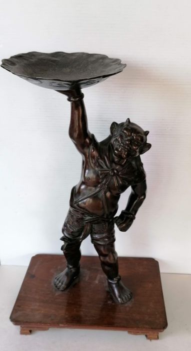 A Japanese bronze figure of Oni, modelled supporting a lotus-form candle stand, moulded signature