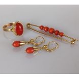 A yellow gold and coral cabochon oval ring in a basket setting with similar brooch and earrings