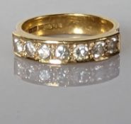 A seven-stone diamond and gold ring in a channel setting, each diamond approximately 0.10 carats