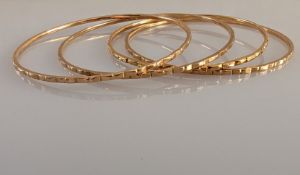 Four gold bangles with carved decoration, each 65mm, unmarked but testing for 18ct gold, 26.4g