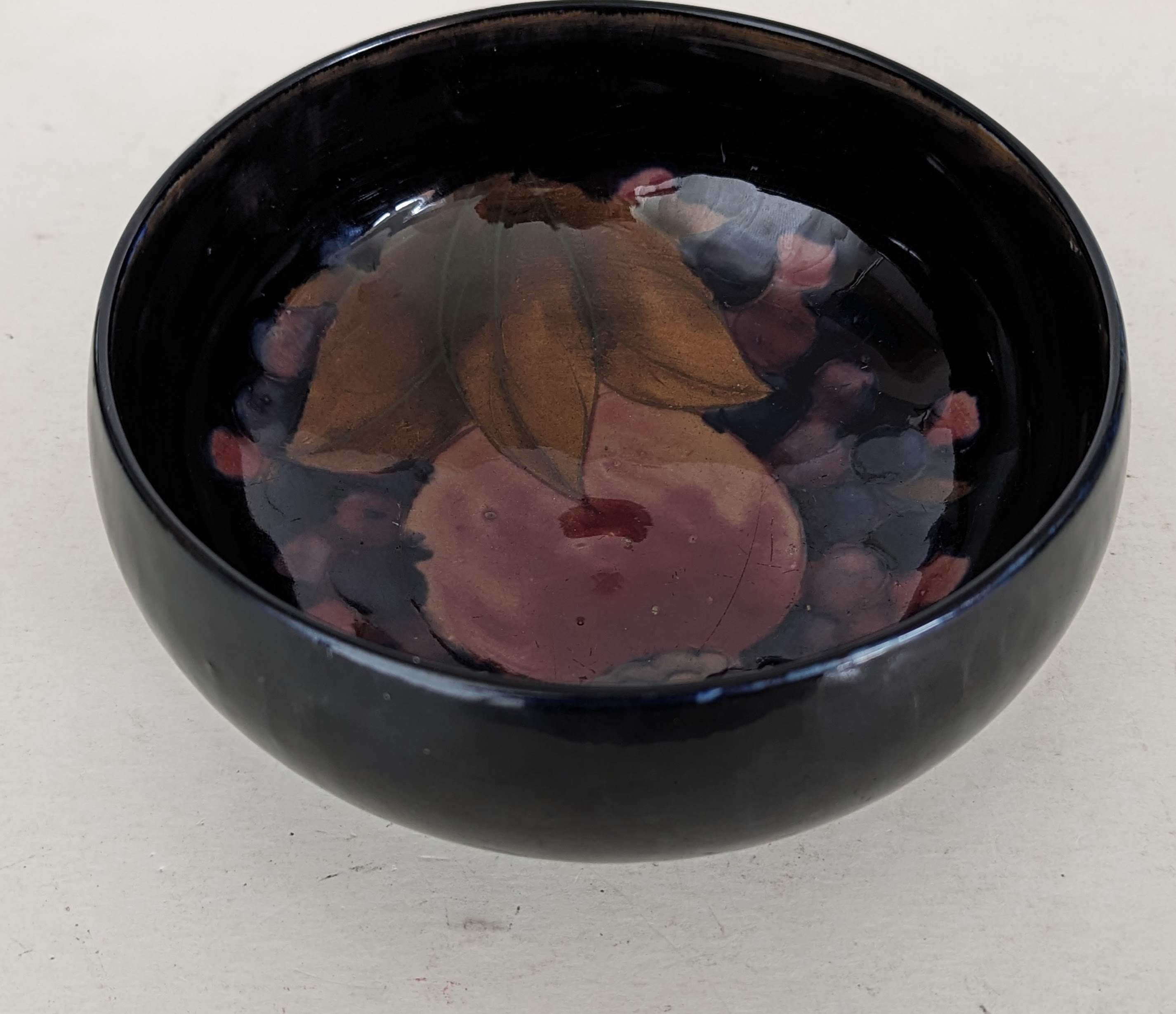 A William Moorcroft pomegranate and berry pattern bowl on a raised foot, 8.5 H x 15.5 cm diameter