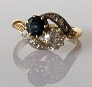 A yellow gold diamond and sapphire two-stone crossover ring in a claw setting with diamond decoratio