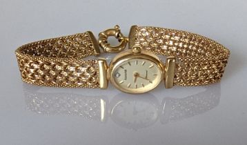 A lady's Accurist 9ct gold oval wrist watch on 9ct gold chain link bracelet with gilt dial and baton