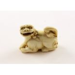 NETSUKE SHISHI, Elfenbein, der liegende Wächterlöwe hat einen beweglichen Ball im geöffneten Maul,