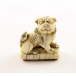 SIEGELNETSUKE, Elfenbein, Fo-Hund auf einer rechteckigen Sockelplatte, Schriftzeichen im Relief, sc