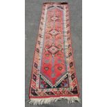 Turkish runner rug ca1950s in red, blue and black depicting the sun around the trim. Measures 265