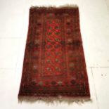 Red ground rug with numerous medallions within large border, ~ 104 cm wide x 184 cm length