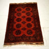 Red ground rug with all over medallions within border & pattern to fringing ~ 128cm x 188cm