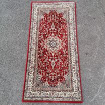 Small red grounded wool rug with cream detail to the border 158cm x 78cm - in good used condition
