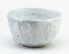 AKIKO HIRAI (born 1970); a lightly faceted stoneware chawan covered in pitted pale grey glaze,