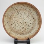 † JOHN WEST for Castle Hedington Pottery; a large stoneware dish covered in oatmeal glaze, impressed