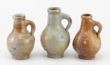 A miniature 18th century German bellarmine type jug of bellied form, height 11cm, and two similar