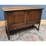 An early 20th century oak sideboard with a pair of linen fold doors, on bun feet, width 137cm, depth