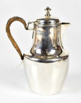 A George V hallmarked silver hot water pot of baluster form with wicker handle, London 1917 (