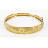 A yellow metal snap bangle stamped 375, approx 9.5g.