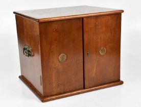 A mahogany twin door specimen coin cabinet containing various coins and tokens.