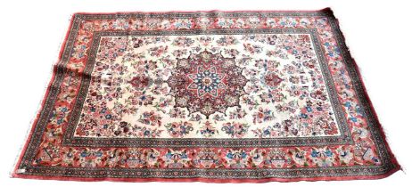 A Persian designed floral decorated large rug with central panel on a cream ground and with pink