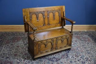 A carved oak monk's bench with panelled front and barley twist columns, width 106cm, depth 50cm,