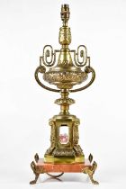 A gilt metal urn table lamp with enamel panels decorated with figures, height including fitting