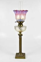 A Victorian brass Corinthian column oil lamp with vaseline and cranberry glass shade above the Hinks