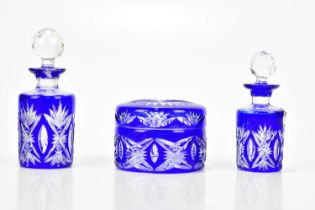 A three piece coloured cut glass dressing table set comprising two scent bottles and a trinket
