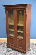A Victorian walnut bookcase, with moulded cornice above two glazed doors, on bun feet, height 194cm,