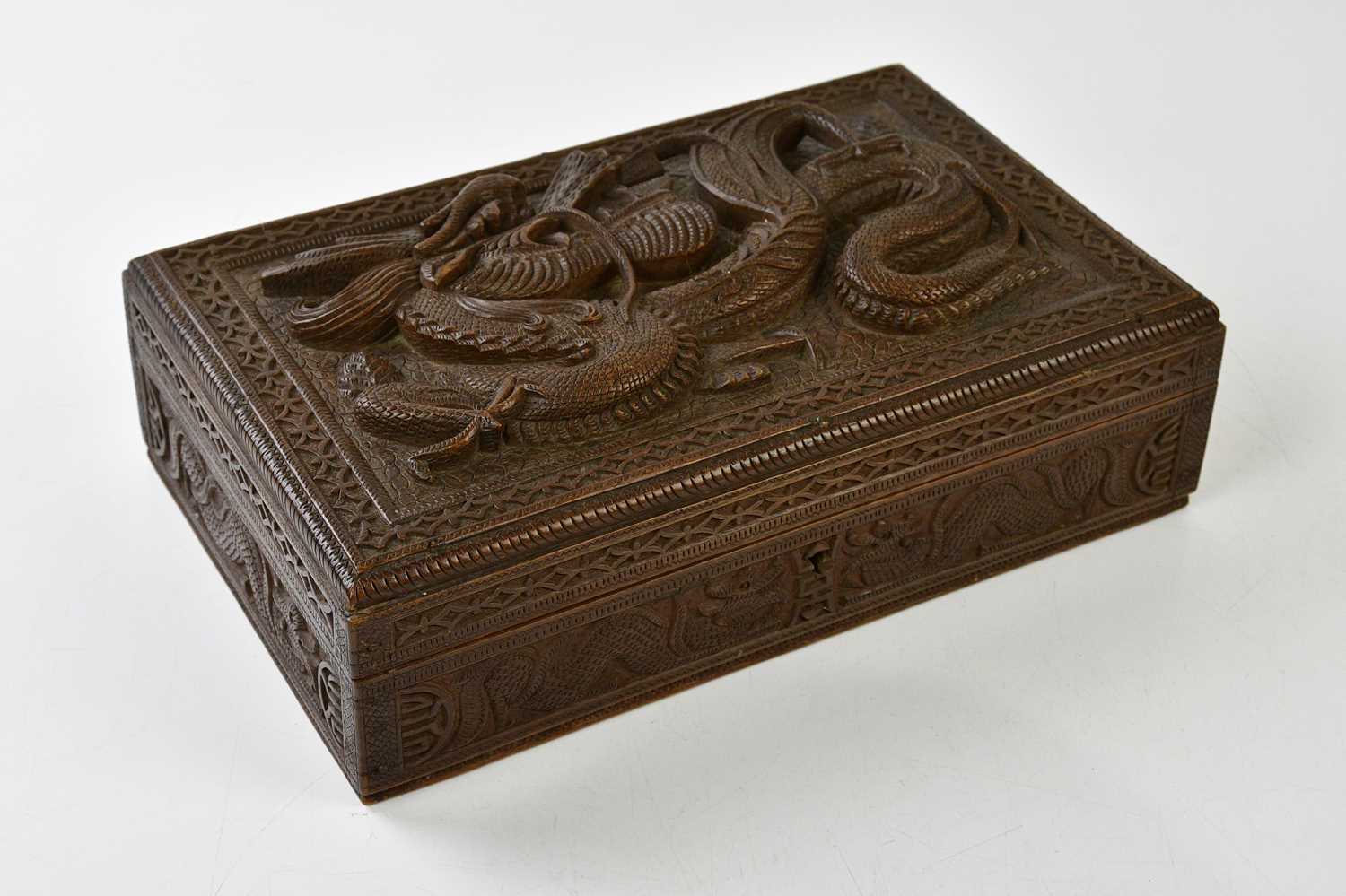 A Chinese hardwood carved box with stylised dragon in relief, height 8cm, width 28cm, depth 18cm.