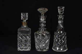 A cut glass decanter with hallmarked silver collar, together with two further cut glass decanters,