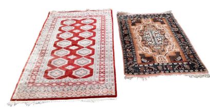 A Caucasian rug worked with a geometric design against a pale ground, with a machine woven red