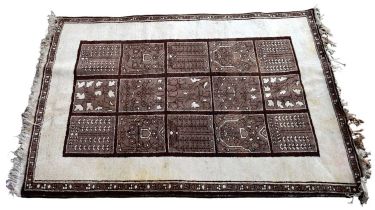 A cream and brown ground rug with central panel set with various devices within a simple border, 205
