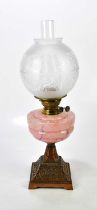 A pink marble effect hand blown 1930s oil lamp, with a copper finish, cast iron base, with brass
