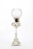 An early 20th century Continental porcelain oil lamp with frosted glass shade above the ceramic
