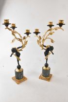 A pair of ormolu and bronze effect three branch figural candelabra with a child supporting three