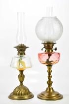 An early 20th century oil lamp, the etched glass shade with floral decoration, with cranberry