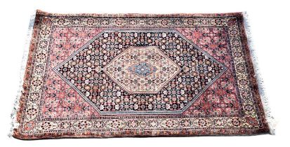 A Persian designed rug with lozenge shaped medallion set with multiple stylised devices within a